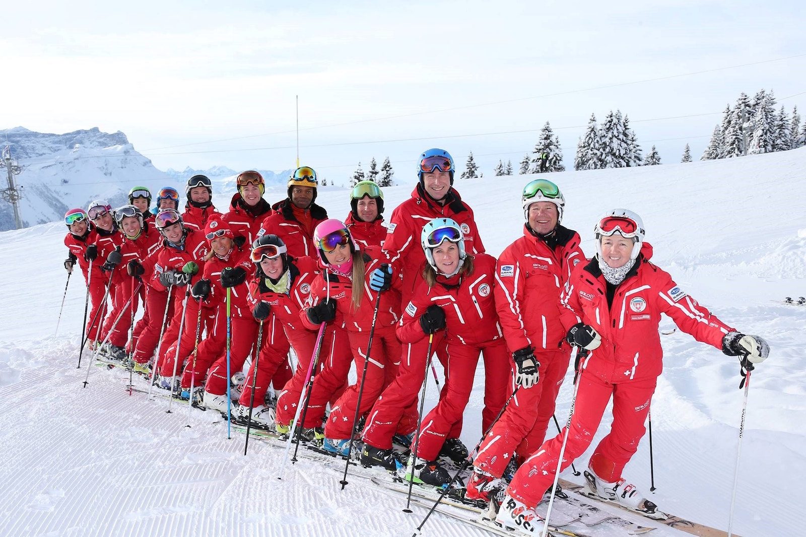 A full line of ski instructors in red uniforms posed on the slope