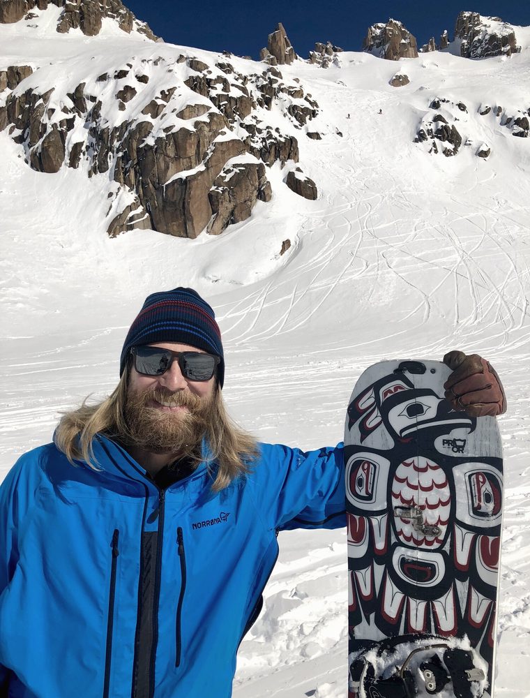 Bass with a splitboard below a steep couloir