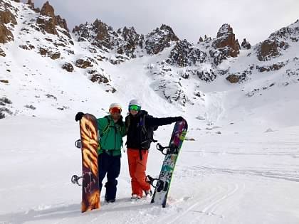 Bass and Madie with snowboards below the granite spires at Refugio Frey